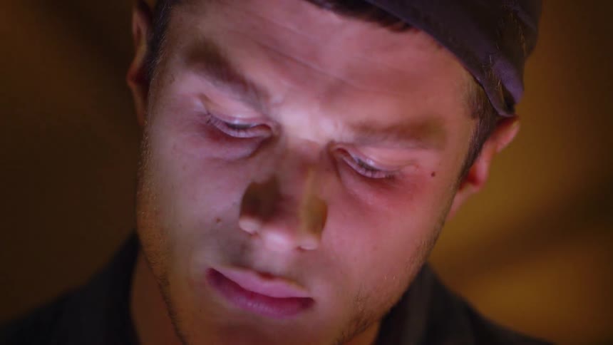 Close up of a man's face being lit up in a dark room