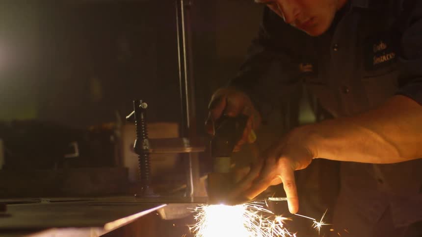 A man is welding metal in a shop