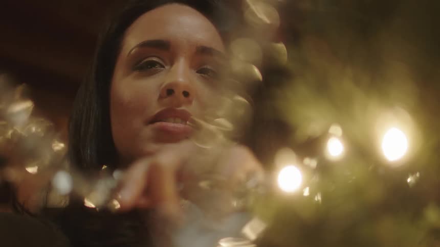 A woman is putting tinsel on a christmas tree