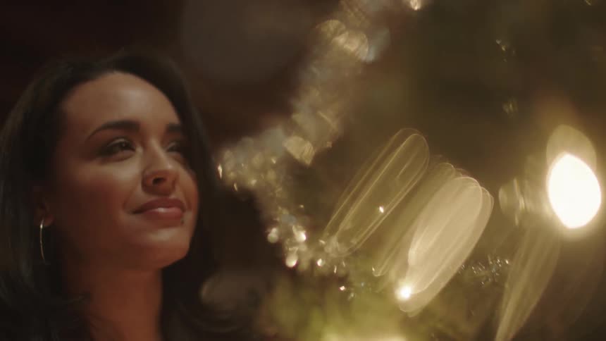 A woman is smiling and adjusting her christmas tree
