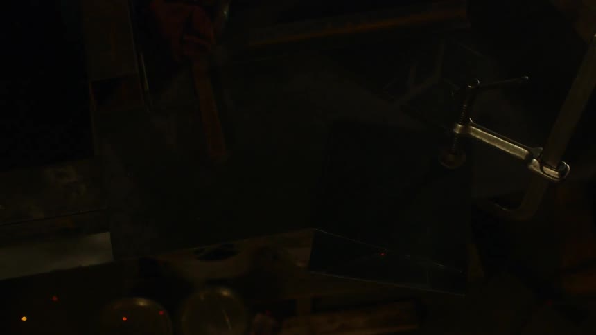 A man welds a piece of metal cutting two lines