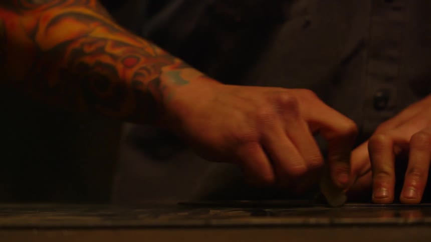A man drawing a line on something with a metal ruler