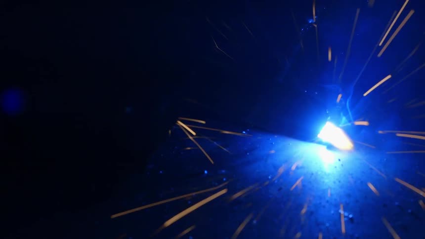 Sparks and blue flames fly as a welder works