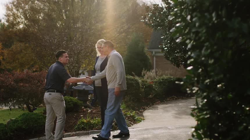 Three people approach each other on a sidewalk and shake hands