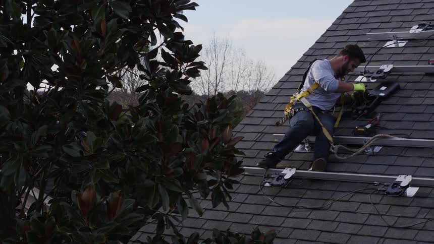 A man is working on the roof installing solar panels