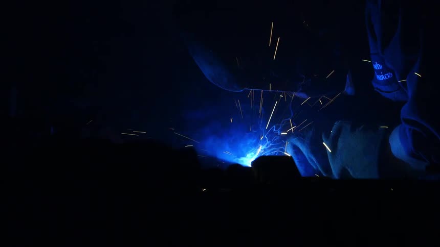Sparks and blue flames fly as a welder works