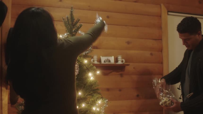 A man and woman are decorating a christmas tree