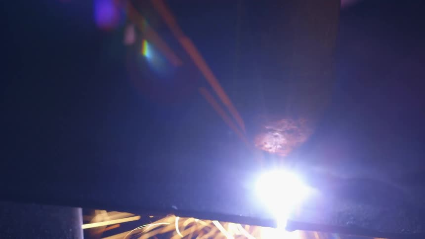 Welder welding a piece of metal with sparks flying under