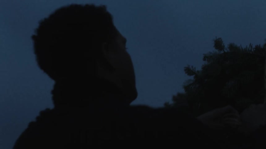 A man is tying a tree to the top of a vehicle at night