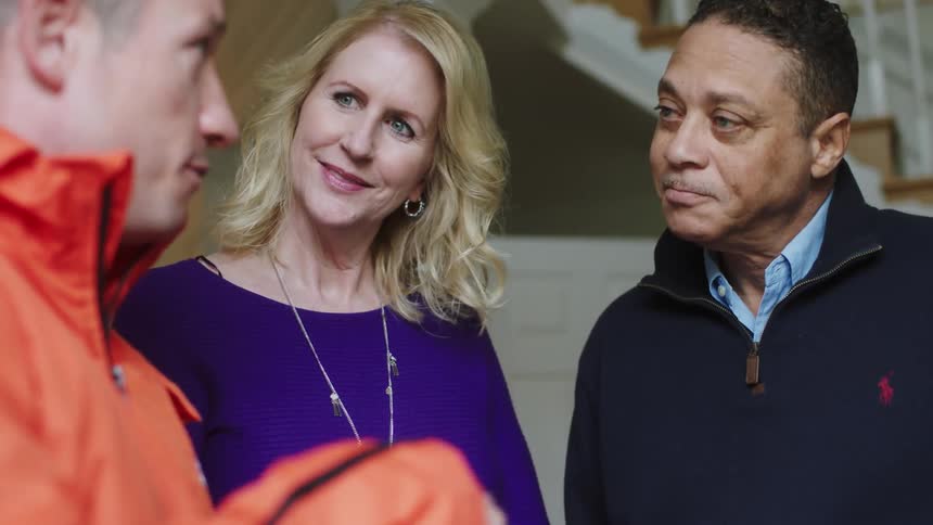 Two men and a woman talk inside a house