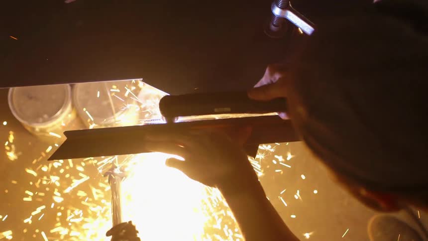 A man is welding metal in his workshop
