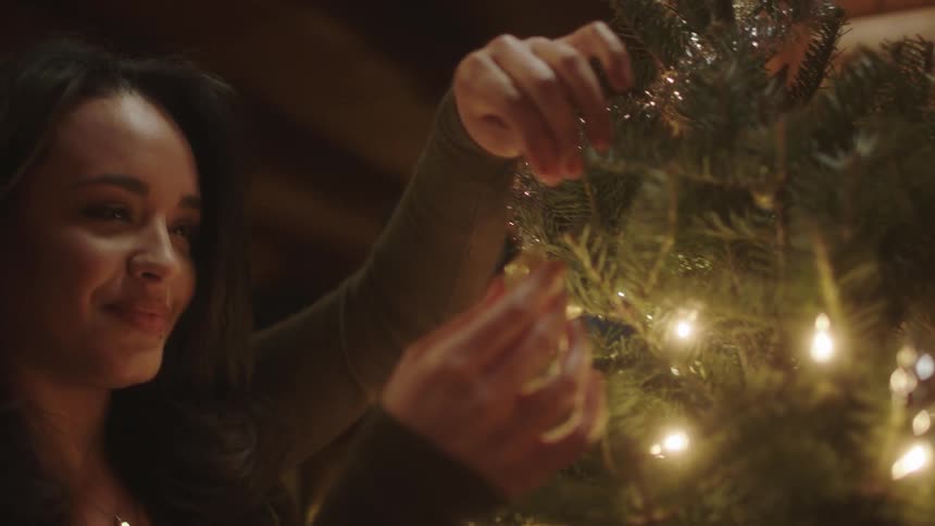 A woman is having fun decorating a christmas tree