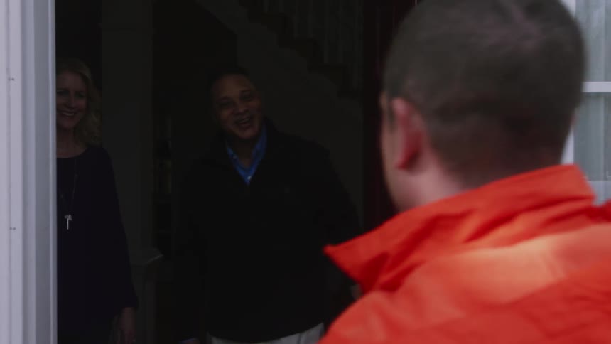 A man knocks on a door and is greeted by a couple
