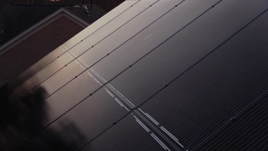 Solar panels cover a house rooftop at sunset