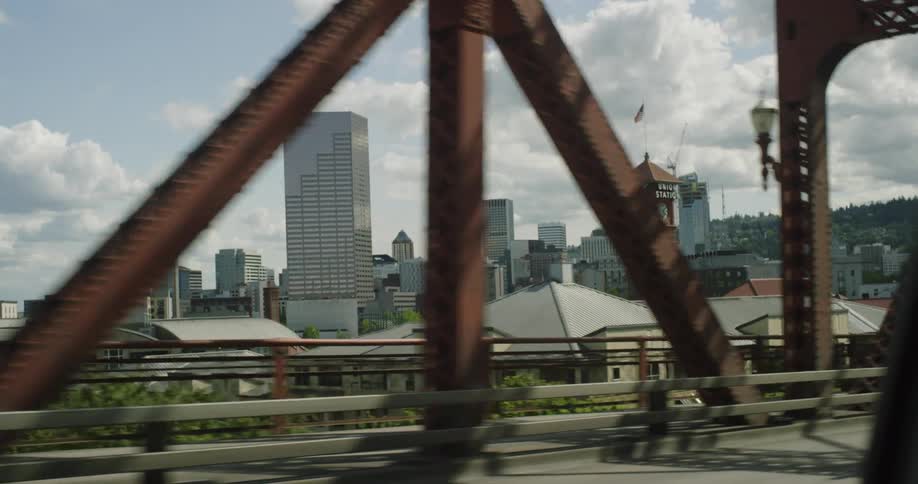 Vehicles driving on a bridge next to a large city