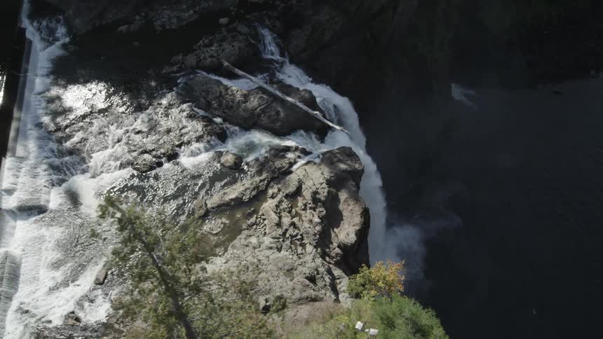 River flowing through rocks over the edge of a waterfall into a pool below