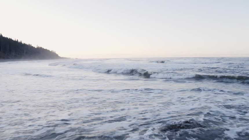 Gentle ocean waves rolling to shore along a rugged coastline