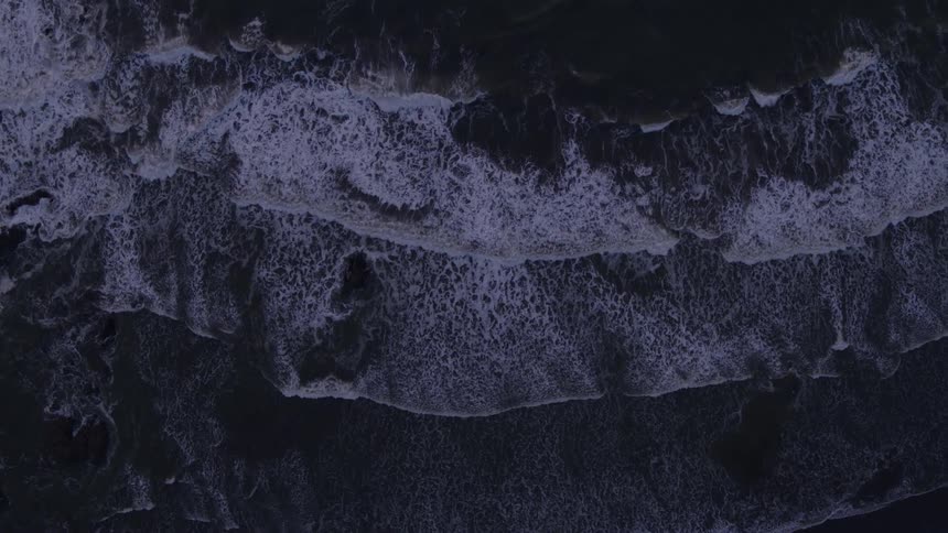 Slow ascent as ocean waves splash and wash ashore at dusk