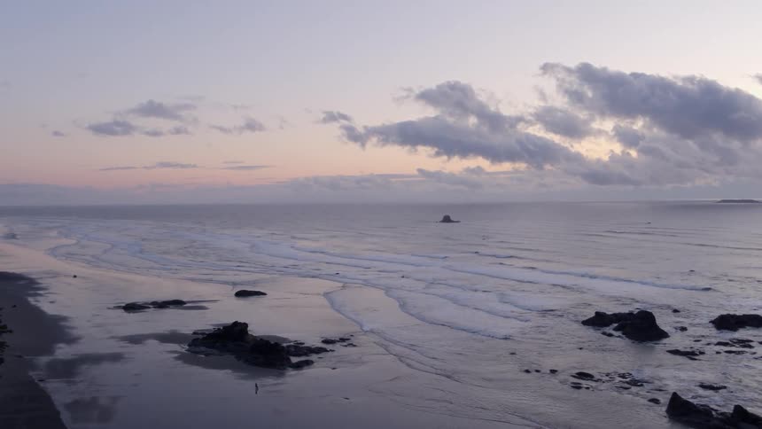 Waves gently wash ashore along a serene ocean beach at sunset