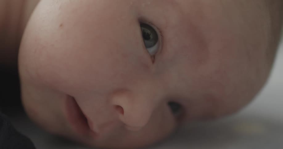 A baby is laying on the bed looking around