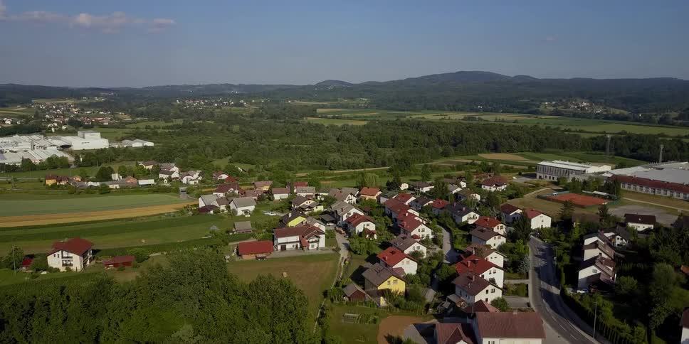 The houses below are surrounded by trees and a small road
