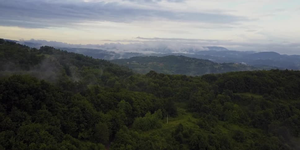 Wispy clouds and fog drift over mountains