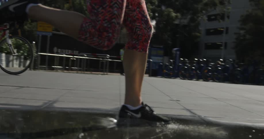 A woman jogs through a puddle of water in an urban area