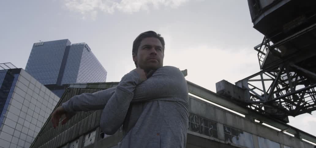 A man stretches outside as a bird flies overhead
