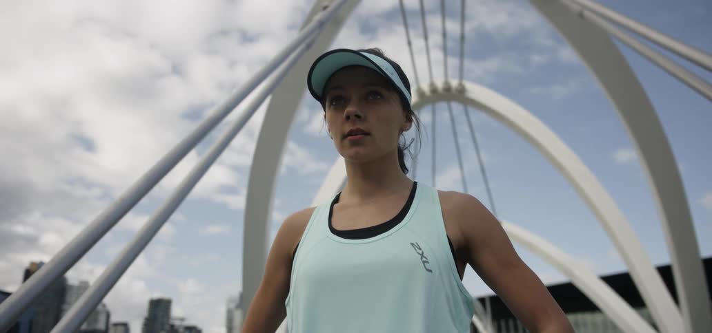 A woman stands on a city bridge