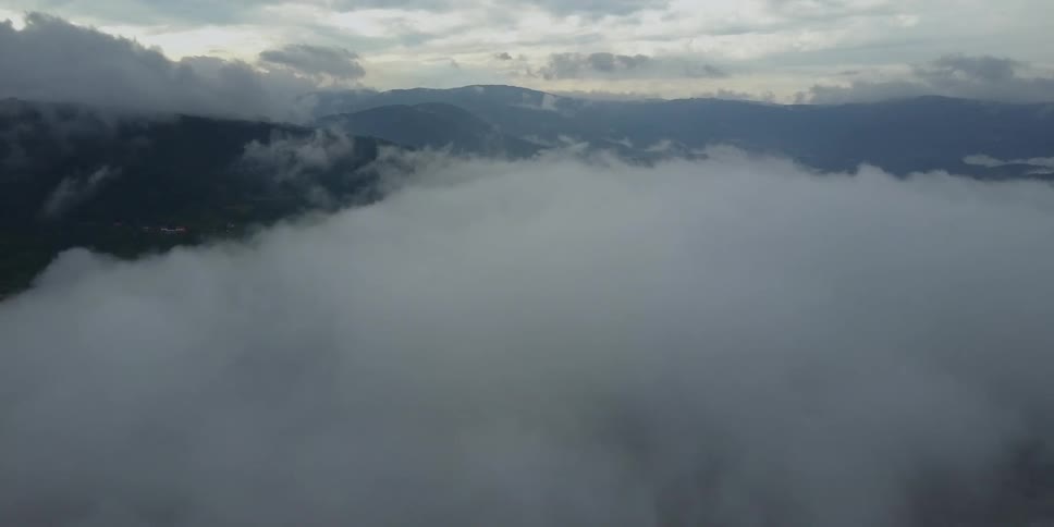 Fog rolls over mountains on a mostly cloudy day