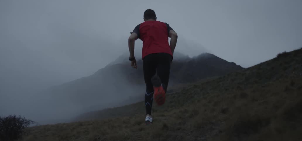 Fog clings to a hill a man is jogging up