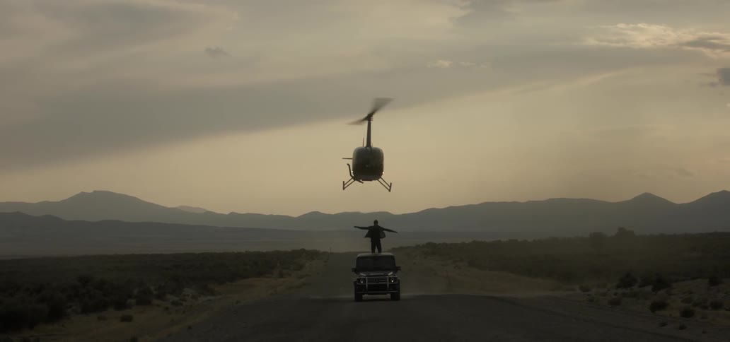 Helicopter hovers low over a jeep and person