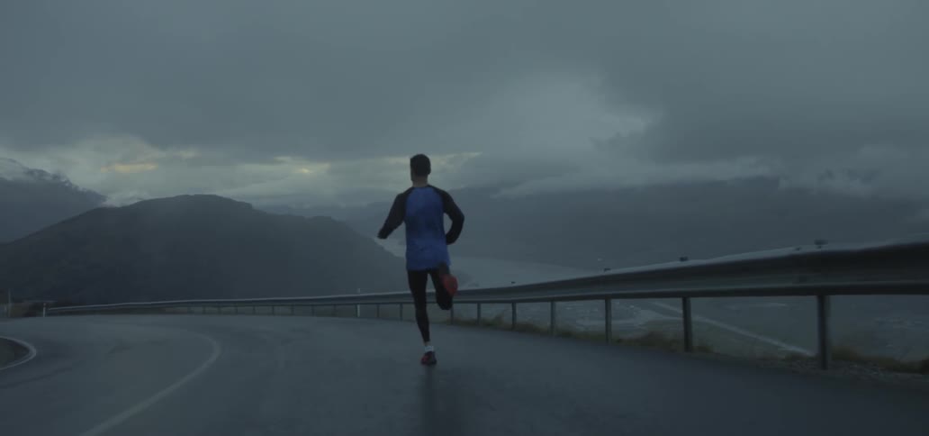 A man jogs on a mountain road on a rainy day