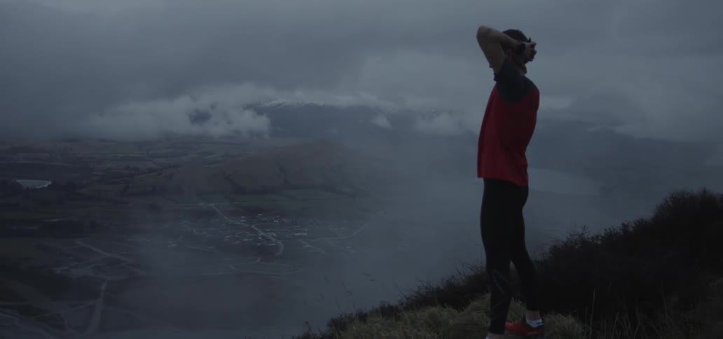 A man is on the mountain stretching his hands behind his head