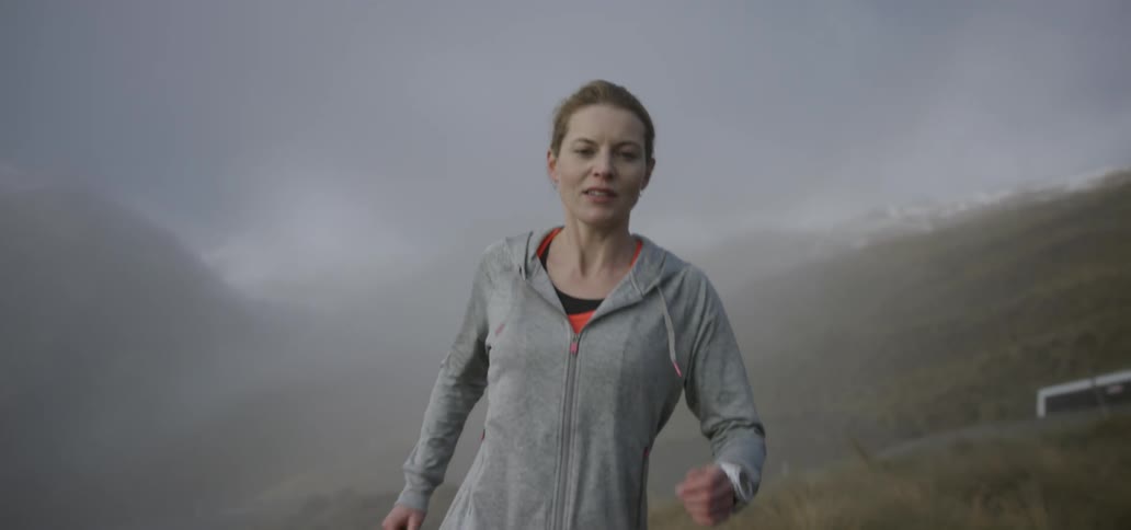 A woman jogs in the mountains on a foggy day