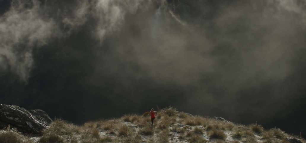 Person running on a high field as ominous clouds gather behind