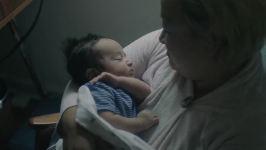 Woman sitting in a rocking chair holding a sleeping baby