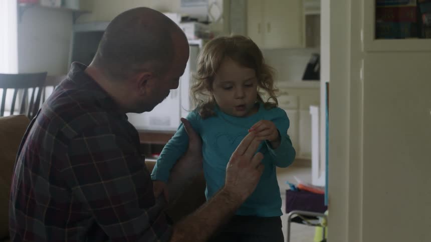 A man holds a small girl and holds up two fingers