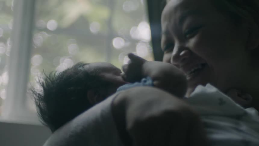 A woman smiles with her baby in her arms