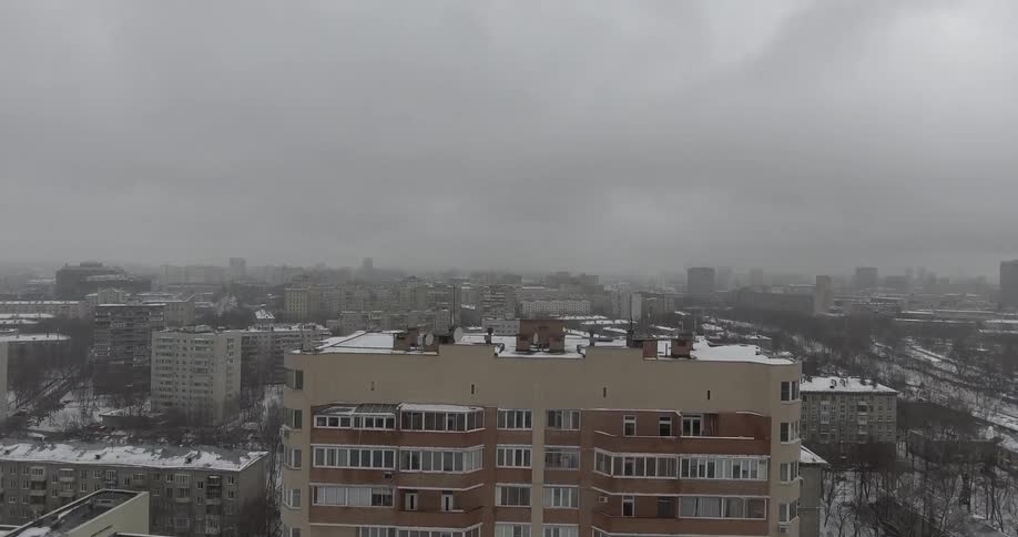 Buildings are shown in a snowy city on a cloudy day