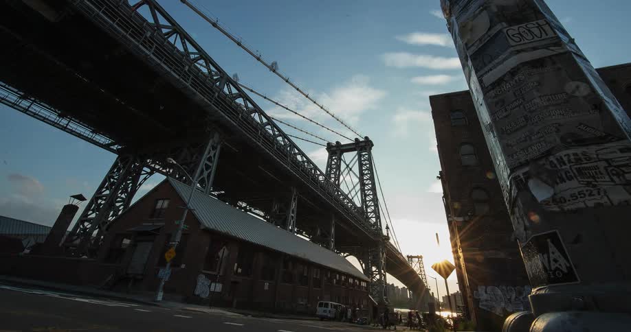 Cars and pedestrians pass beneath a city bridge