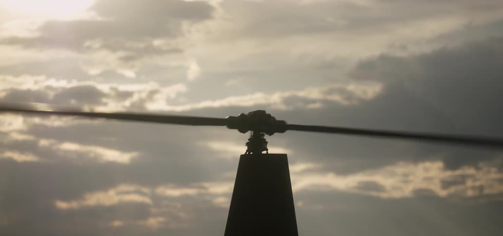 A helicopter propeller spins on a cloudy day