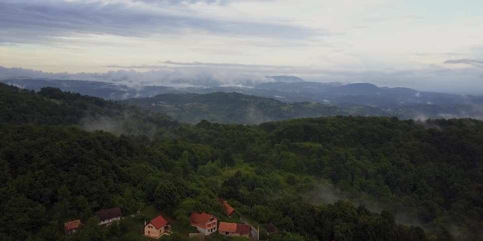 A small group of houses are on this green mountain