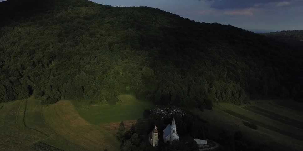 A church sits in shadow at the base of a mountain