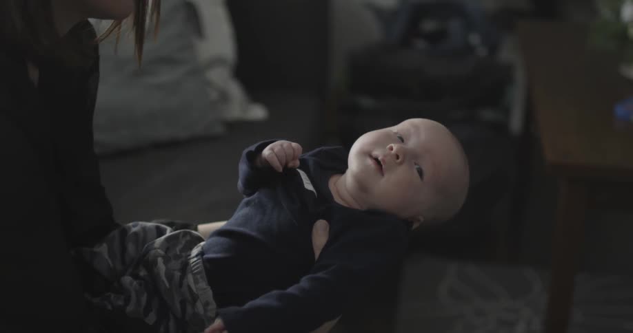 A woman is holder a baby and smiling