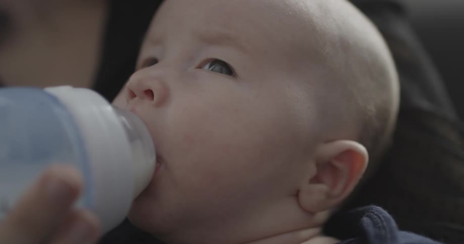A baby is drinking milk from a bottle