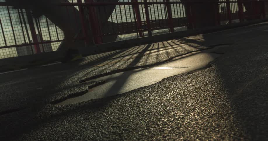 Long shadows stretch across a section of road on a bridge