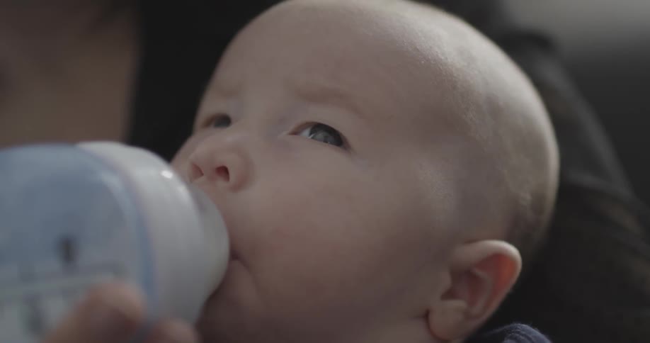 A woman feeds an infant with a bottle