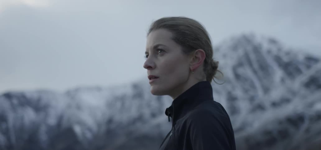A woman stands in the snowy mountains