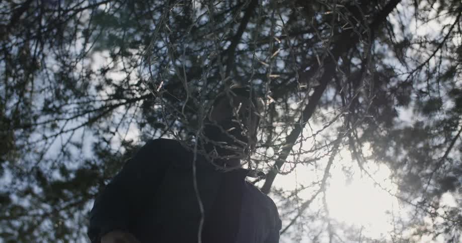 A man is hanging a circular cage outside during the day